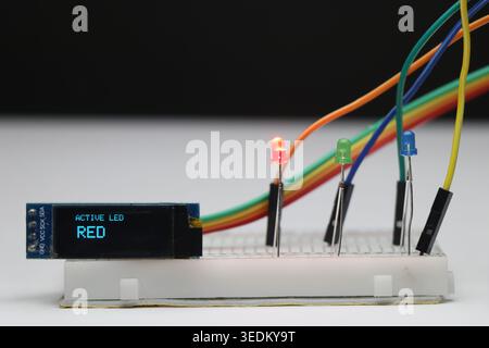 Red LED is glowing on the breadboard among the other color LED and the OLED display module is showing message Stock Photo