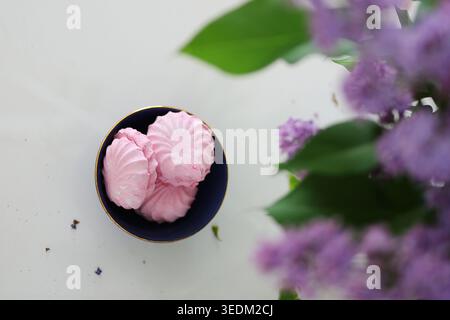 Romantic spring composition with pink desserts, floral bouquet and handmade mug in bright minimalist interior. Stock Photo