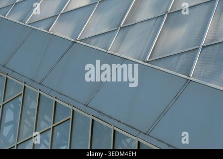 Sunlight glimmers on the glass and metal structure, revealing sharp angles and design. Stock Photo