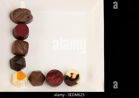 Assorted Belgian Chocolates Arranged in L-Shape on Square White Plate Stock Photo