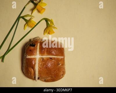 Easter hot cross bun with daffodil flowers yellow background Stock Photo