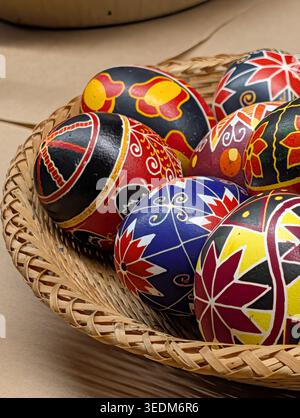 colorful Ukrainian Pysanky Easter eggs with intricate folk motifs in a woven wicker basket. Detailed macro view of hand-painted Easter eggs. Stock Photo