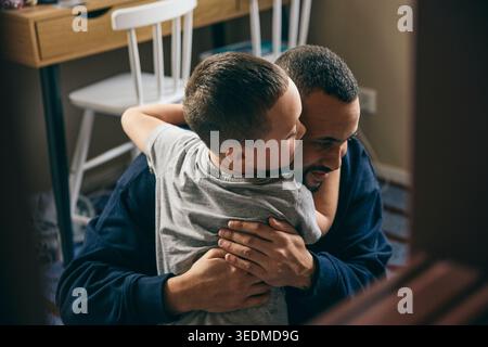 Affectionate boy embracing father at home Stock Photo