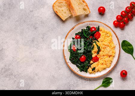 Cooked omelette and spinach with tomatoes on a light background, top view. Stock Photo