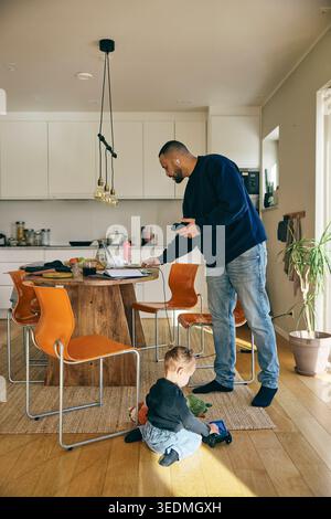 Girl playing with toys while father working from home Stock Photo