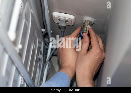 A worker installing or repairing a plumbing valve, likely for a washing machine Stock Photo