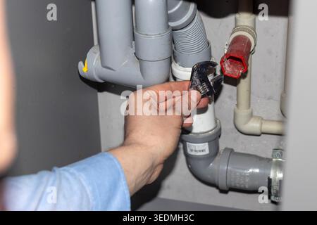 Plumber working on the plumbing drain pipes under a sink Stock Photo