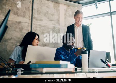 Smiling male and female employees discussing strategies with investor at office Stock Photo