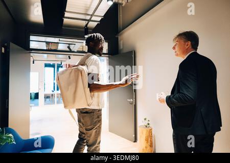 Male employee talking with investor while walking in office corridor Stock Photo