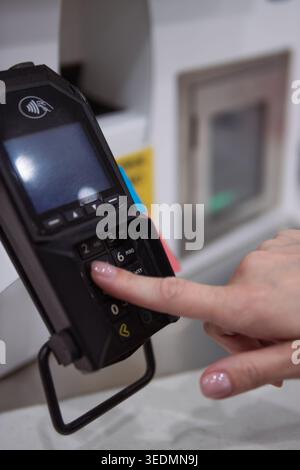 Hand entering pin code on a credit card payment terminal with emv chip and contactless tapping rfid reader for transaction, purchasing services, and m Stock Photo
