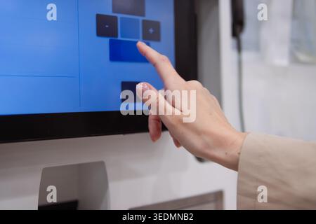 Person interacting with a modern touchscreen display. A woman's finger touching the digital interface. Navigating an automated kiosk or smart system. Stock Photo