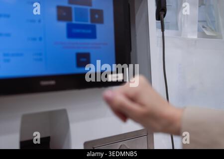 Person interacting with a self-service checkout terminal, utilizing a digital touchscreen for an automated transaction, representing retail innovation Stock Photo