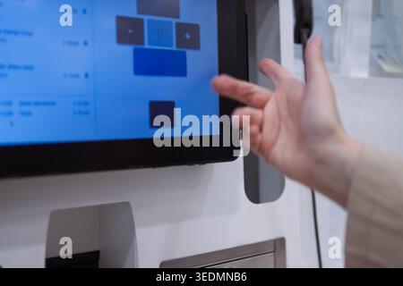 Hand interacting with a self-service interactive digital touchscreen kiosk. Selecting options for ordering or payment. Using modern technology for eff Stock Photo