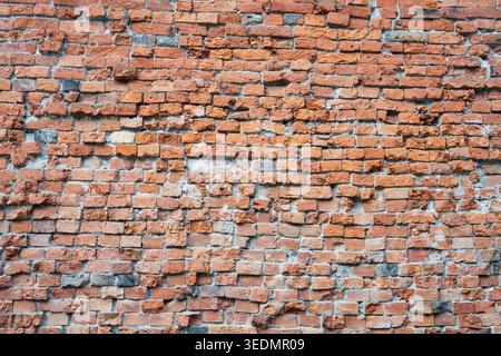 Background of an ancient weathered red brick wall with irregular masonry and rough texture . Old rustic orange brickwork surface for vintage industria Stock Photo