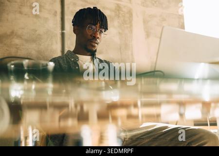 Focused businessman working on laptop while sitting at glass desk in office Stock Photo
