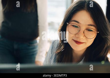 Smiling female business professional wearing eyeglasses at office Stock Photo