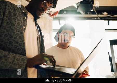 Focused computer programmers working on laptop at startup workspace Stock Photo