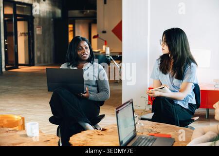 Female entrepreneur having conversation with team at modern startup office Stock Photo