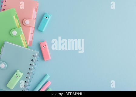 Pastel school supplies, including notebooks, binders, pens, cute highlighters, neatly arranged on a light blue background providing copy space Stock Photo