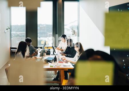 Group of diverse computer programmers working together while sitting around table at creative workspace Stock Photo