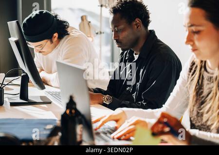 Group of focused programmers working on computers at desk in office Stock Photo