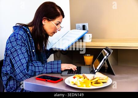 Woman working remotely during morning breakfast routine Stock Photo