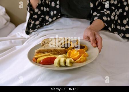 Person holding breakfast in bed for morning routine Stock Photo