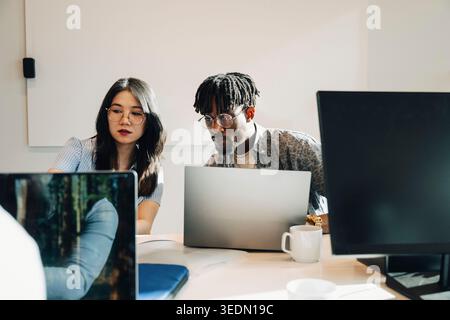 Group of male and female programmers working together on laptop at modern startup office Stock Photo