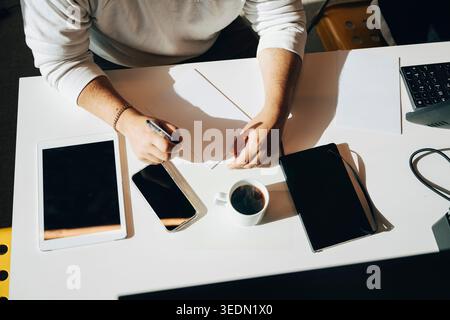 High angle view of businessman writing notes on paper at white desk Stock Photo