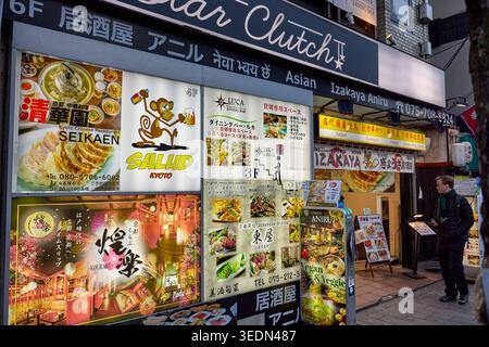 A man looking at menus at izakaya entrance at Pontocho, a narrow, atmospheric alley lined with old picturesque buildings in Kyoto, Japan. Stock Photo