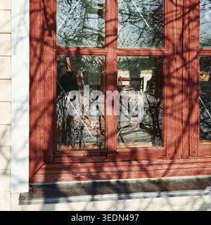 View through old red wooden window with chair in interior Stock Photo