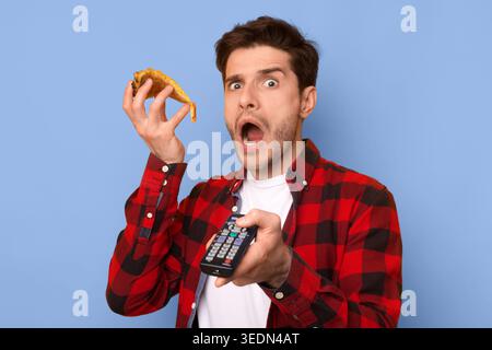 Man Holds Taco in One Hand and Remote Control in the Other While Looking Surprised Stock Photo
