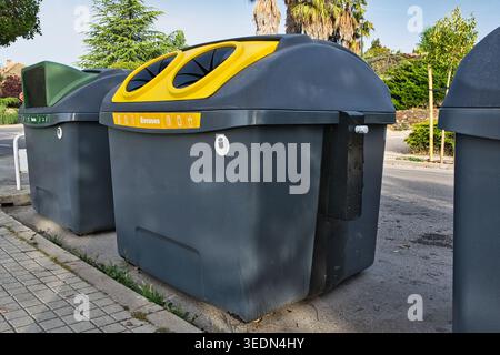Public recycling containers for packaging waste on a city street in Spain. Urban waste management scene showing yellow and green recycling bins. Stock Photo