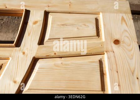 Close-up of new unfinished wooden door with natural pine texture and carved decorative panels. Carpentry, woodworking, renovation, and interior design Stock Photo