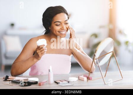 Woman Applying Skincare in Bathroom With Makeup Products on Table During Day Stock Photo
