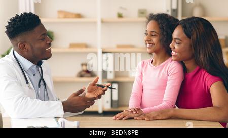Doctor Talking With Mother and Daughter in Clinic During Routine Checkup Session Stock Photo