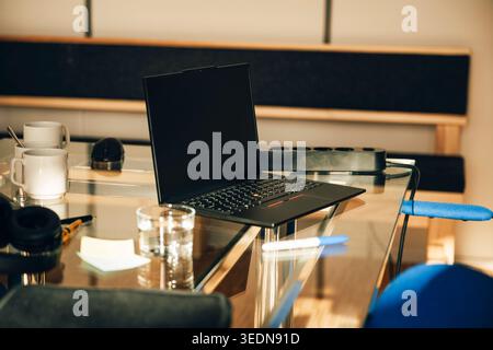 Black laptop with blank screen on glass desk in modern office Stock Photo