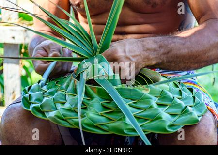 Local artisan from Serra Grande on the southern coast of Bahia making a hat from a coconut palm leaf. Stock Photo