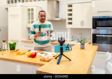 Male vlogger recording cooking tutorial in kitchen Stock Photo