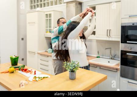 Happy couple dancing and cooking together in bright modern kitchen Stock Photo