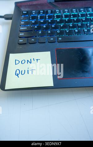 Motivational "Don't Quit" sticky note on a laptop keyboard Stock Photo