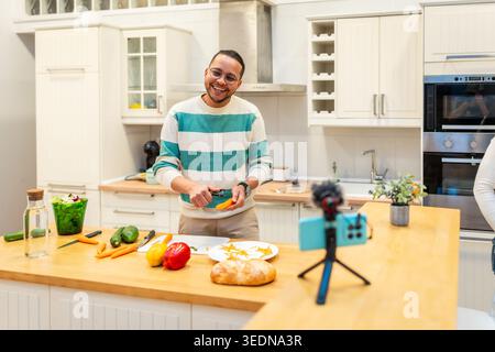 Influencer peeling vegetables for cooking video content Stock Photo