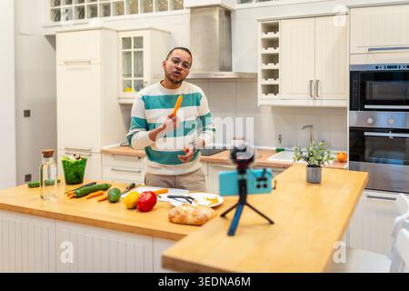 Man vlogger recording cooking video in kitchen Stock Photo