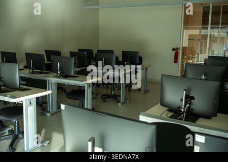 Dark Empty Computer Lab with Rows of Monitors in Dim Light Stock Photo