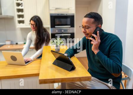 Couple working remotely in kitchen communicating and collaborating from home Stock Photo