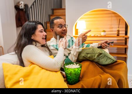 Young couple laughing watching movie night at home Stock Photo