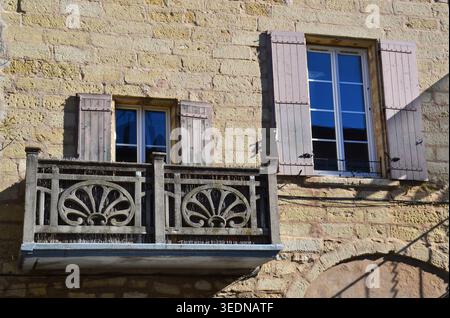 Traditional stone facade with wooden shutters and a decorative carved balcony in the historic village of Sommieres, France. Stock Photo