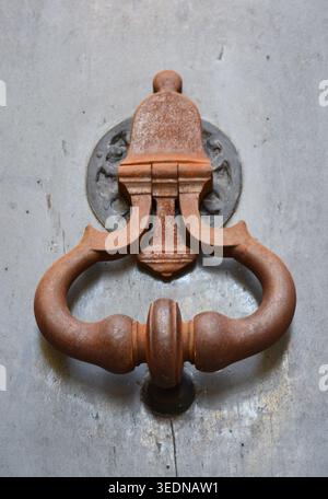 Antique rusty iron door knocker on a weathered grey door Stock Photo