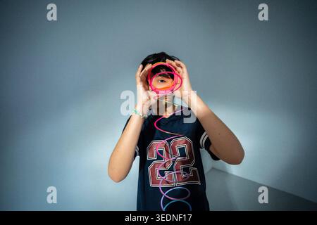 Portrait of boy wearing number 22 jersey playing with spiral toy against wall Stock Photo