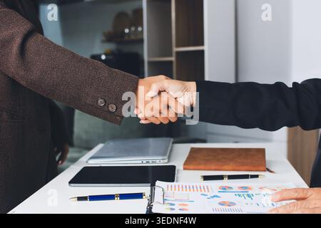 Close up of business people shaking hands on meeting in office. Stock Photo